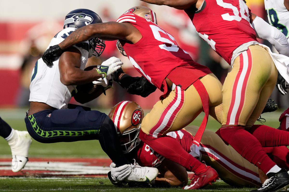 Seattle Seahawks running back Kenneth Walker III, left, is tackled by San Francisco 49ers defensive end Nick Bosa, bottom, and linebacker Dre Greenlaw during the first half of an NFL football game in Santa Clara, Calif., Sunday, Dec. 10, 2023. (AP Photo/Godofredo A. Vásquez)