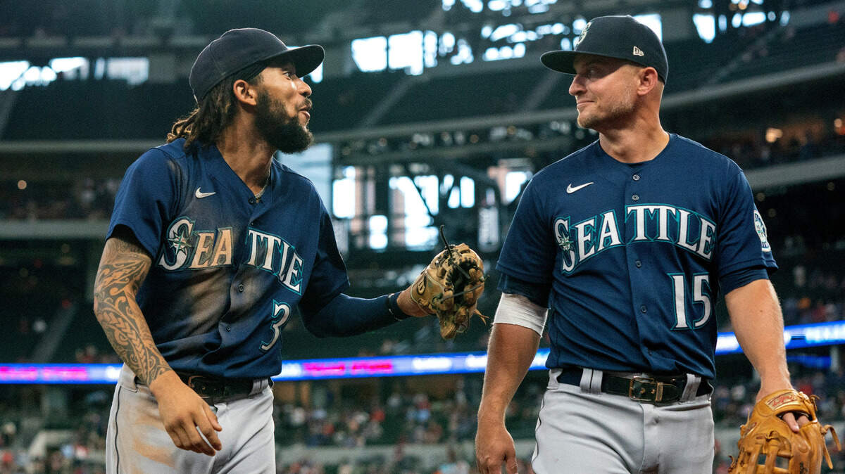 Seattle Mariners shortstop J.P. Crawford (3) jokes with third baseman Kyle Seager (15) during a baseball game against the Texas Rangers Thursday, Aug. 19, 2021, in Arlington, Texas. Seattle won 9-8 in 11 innings.