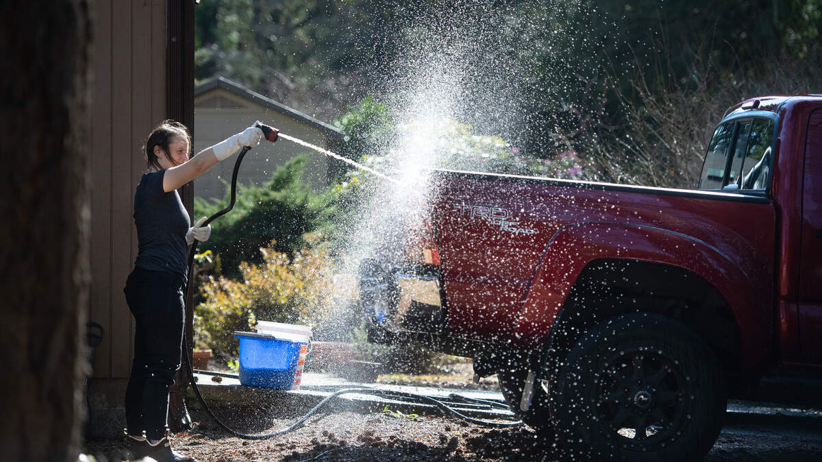 Holly Anderson hoses down her truck as she gives it a wash in the sunshine outside her home in Tumwater, Washington, on Saturday, March 18, 2023.