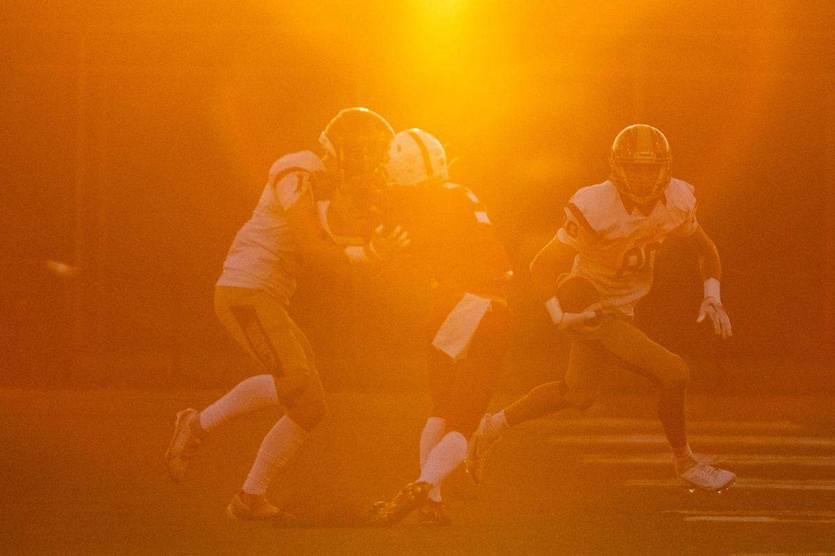 The setting sun lowers through the trees west of Steilacoom High School as Enumclaw’s Karson Holt (80) runs up field after catching pass from quarterback Gunnar Trachte during the first quarter of a 2A SPSL game on Friday, Sept. 15, 2023, in Steilacoom, Wash.