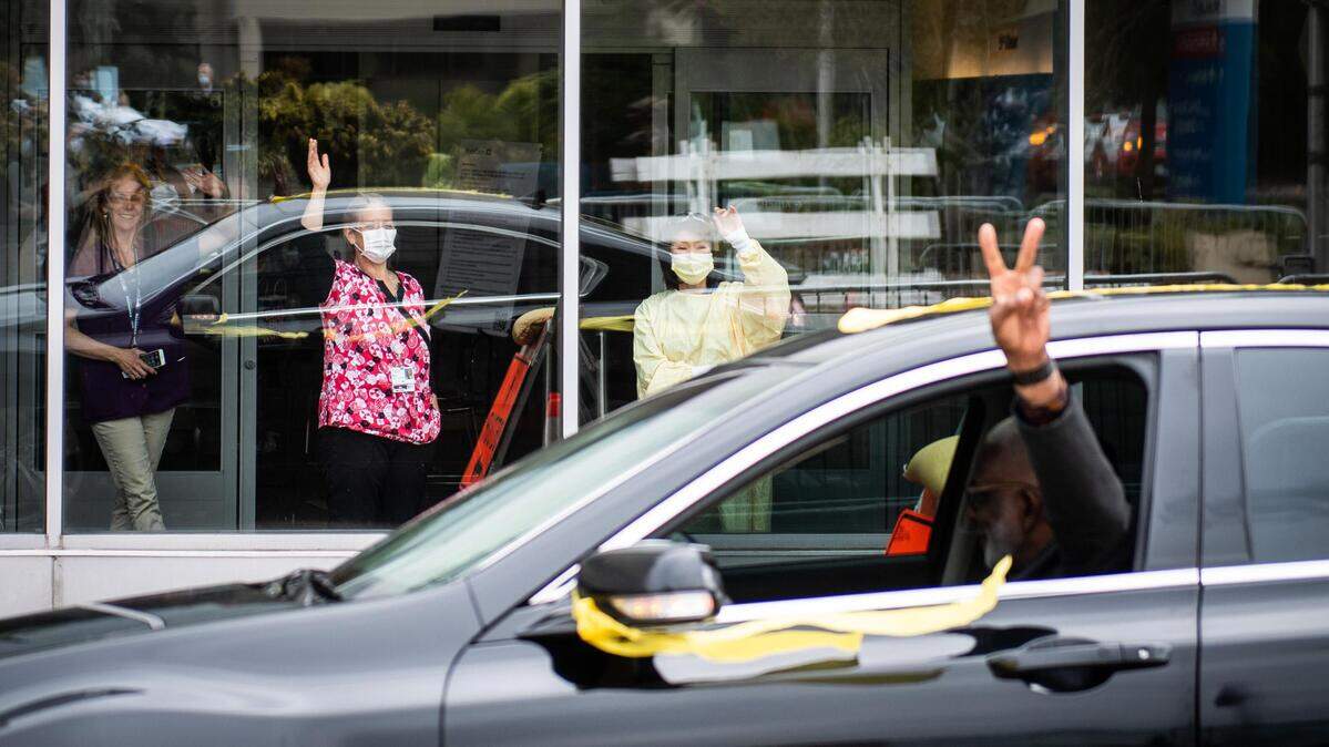 Health care workers wave as cars filled with people from groups including the Hilltop Business Association, Tacoma Ministerial Alliance and, SEIU 1199 Northwest drive by and honk horns in support of health care workers outside  MultiCare Tacoma General Hospital in Tacoma on Friday, April 24, 2020.