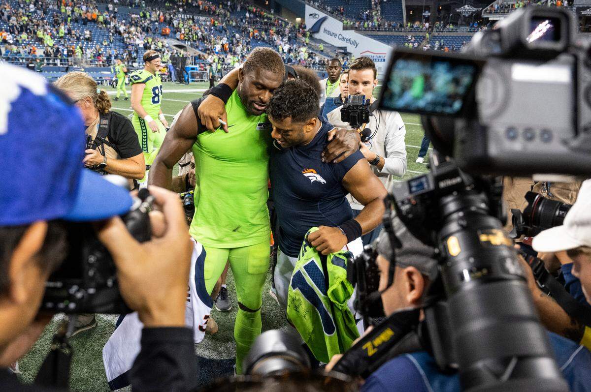 Seattle Seahawks wide receiver DK Metcalf (14) and Denver Broncos quarterback Russell Wilson (3) hug after the Seattle Seahawks defeated the Denver Broncos 17-16 at an NFL game on Monday, Sept. 12, 2022, at Lumen Field in Seattle.