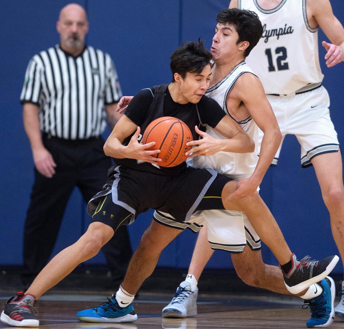 Puyallup’s Taki Uluilakepa runs into the no-bend defense of Olympia’s Alfredo Ramirez-Cortes during Saturday night’s SPSL 4A boys basketball game at Olympia High School on Jan. 4, 2020.