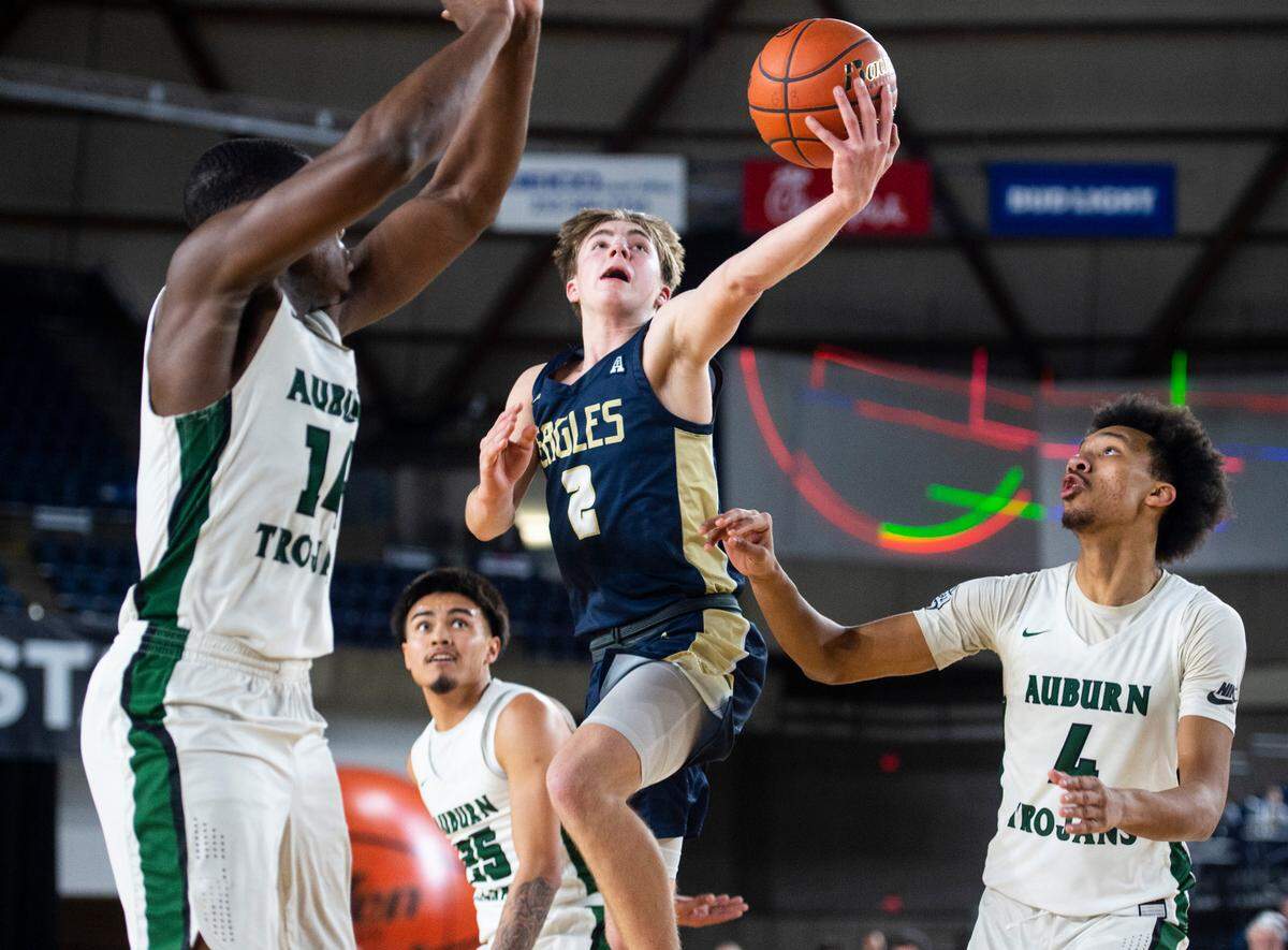 Arlington guard Leyton Martin (2) goes to make an underhanded layup as Auburn guard Luvens Valcin (14) defends during an opening round game at the WIAA state basketball tournament in the Tacoma Dome in Tacoma, Washington, on Wednesday, March 1, 2023. Auburn won the game 52-41.