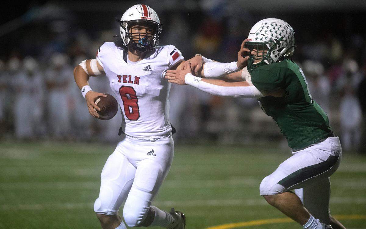 Yelm quarterback Damian Aalona holds off Peninsula linebacker Jones Stalker before tossing a touchdown pass to Kyler Ronquillo during Friday night’s football game at Roy Anderson Field in Purdy, Washington, on Oct. 21, 2022.