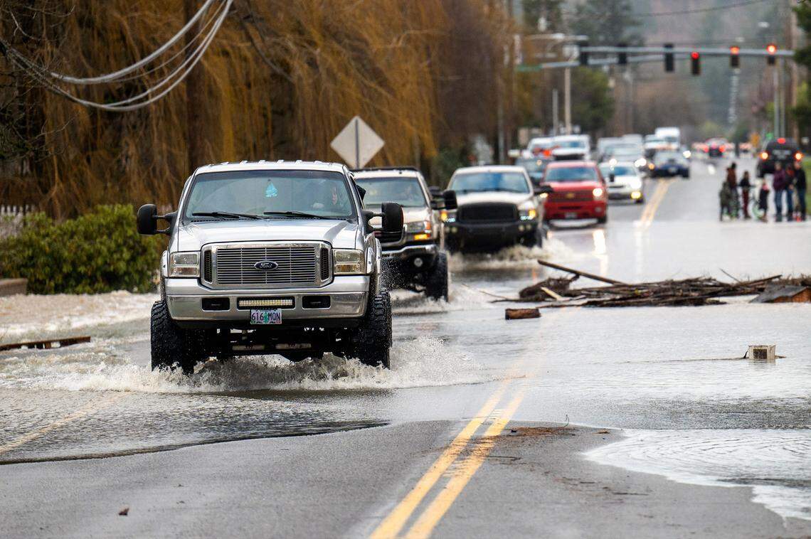 A cavalcade of large pickup trucks makes its way south along Highway 507 through floodwaters from the Skookumchuck River on Friday, Jan. 7, 2022, in Centralia, Wash.
