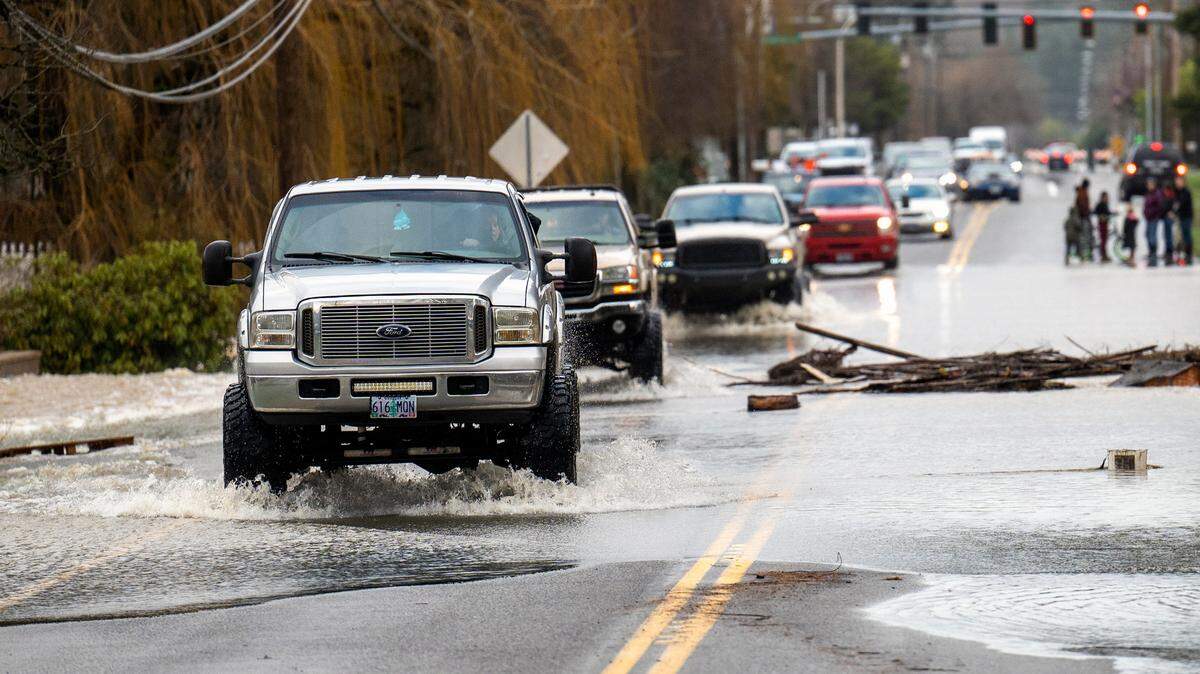 A cavalcade of large pickup trucks makes its way south along Highway 507 through floodwaters from the Skookumchuck River on Friday in Centralia.
