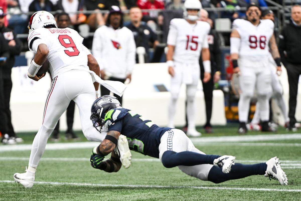 Seattle Seahawks safety Jamal Adams (33) wraps up the ankles of Arizona Cardinals quarterback Joshua Dobbs (9) during the first quarter of the game at Lumen Field, Sunday, Oct. 22, 2023, in Seattle, Wash.