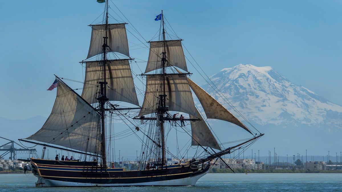 As Mount Rainier looms in the background, crew on the tall ship Lady Washington work to drop a final sail during a training exercise on Tacoma’s Commencement Bay in 2019. The Lady Washington, launched in 1989, is a full-scale replica of a colonial era ship of the same name. It is the state’s official tall ship.