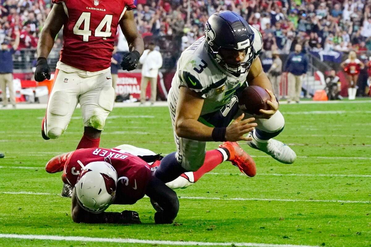 Seattle Seahawks quarterback Russell Wilson (3) dives for a touchdown as he gets past Arizona Cardinals safety Budda Baker, left, during the second half of an NFL football game Sunday, Jan. 9, 2022, in Glendale, Ariz. (AP Photo/Darryl Webb)