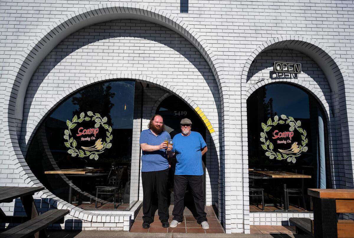 Scamp Brewing owner Arthur Cohn, left, and his father, Jim Cohn, right, cheers to their second taproom at 5419 South Tacoma Way on Wednesday night.