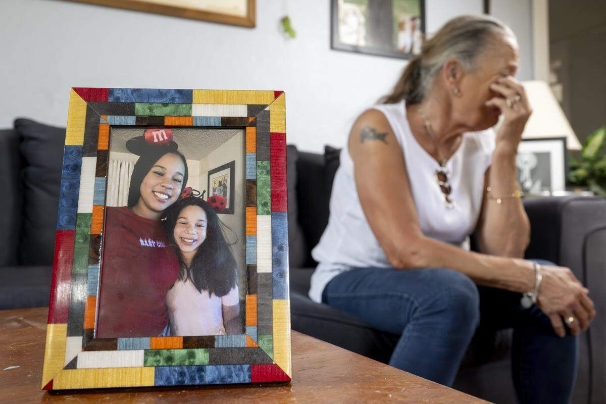 A photo of sisters Ka'Lani Buchanan, left, and Kassidy Buchanan, 14, who has been missing since the fall of 2024, sits in front of their grandmother Joyce Robinson, who wipes away tears as she talks about Kassidy, on Tuesday, Aug. 5, 2025, at her home in Tacoma, Wash.