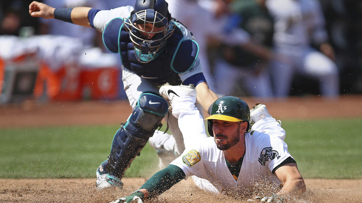 Oakland Athletics’ Matt Joyce slides to score beneath the tag of Seattle Mariners catcher Mike Zunino in the sixth inning of a baseball game Sunday, Sept. 2, 2018, in Oakland, Calif. Joyce scored on a single by A’s Marcus Semien. (AP Photo/Ben Margot)