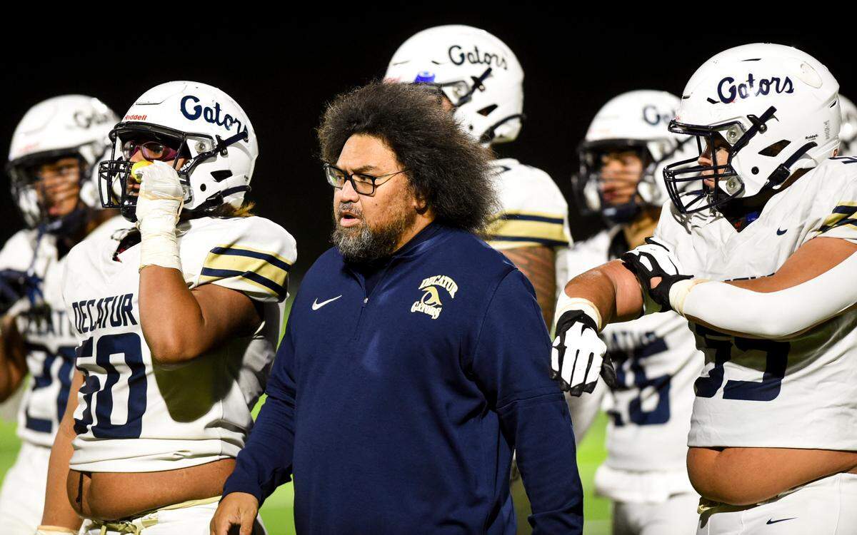 Decatur head coach Matthew Vaeena and players walk off the field during the first half of the game against the Federal Way Eagles at Federal Way Memorial Stadium, Thursday, Oct. 26, 2023, in Federal Way, Wash.