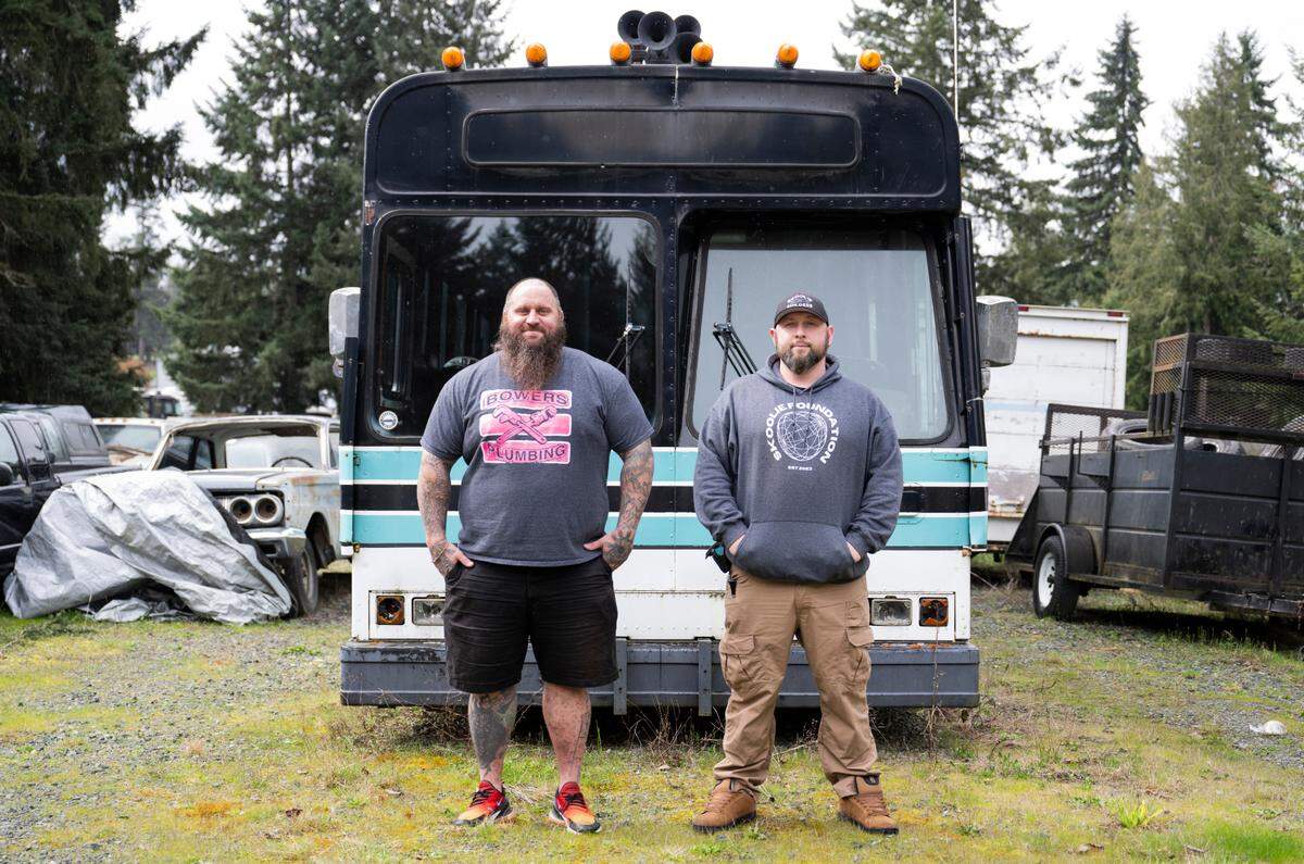 Skoolie Foundation board members Joe Bowers and Brandon Simmons pose in front of the Empowerment bus, that will be a mobile-hygiene bus. Photographed at Bowers Plumbing & Remodel, on March 25, 2024, in Puyallup.