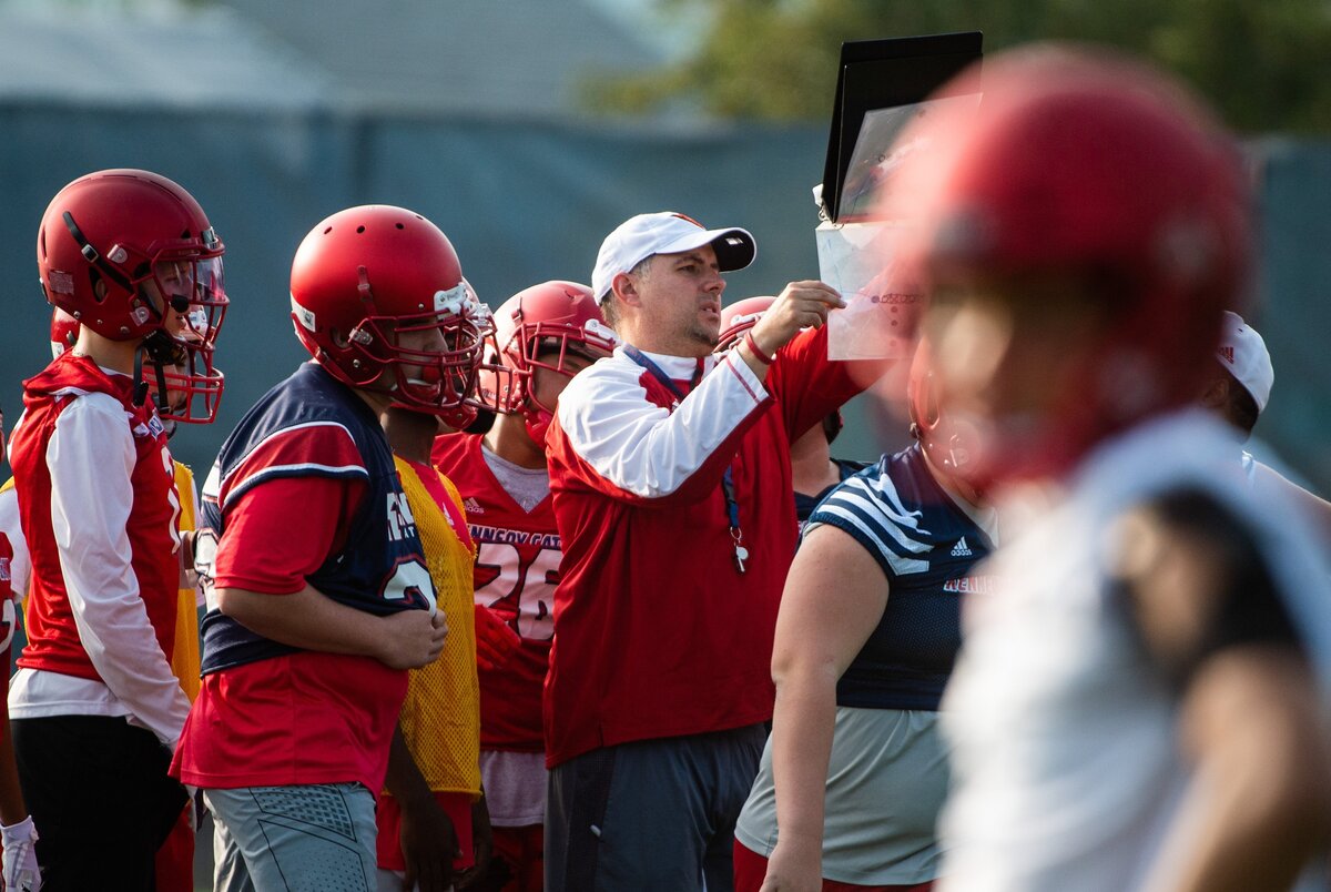 Head coach Sheldon Cross goes over a play during Kennedy Catholic High School football practice at Kennedy Catholic High School in Burien, Wash., on Thursday, Aug. 16, 2018. .