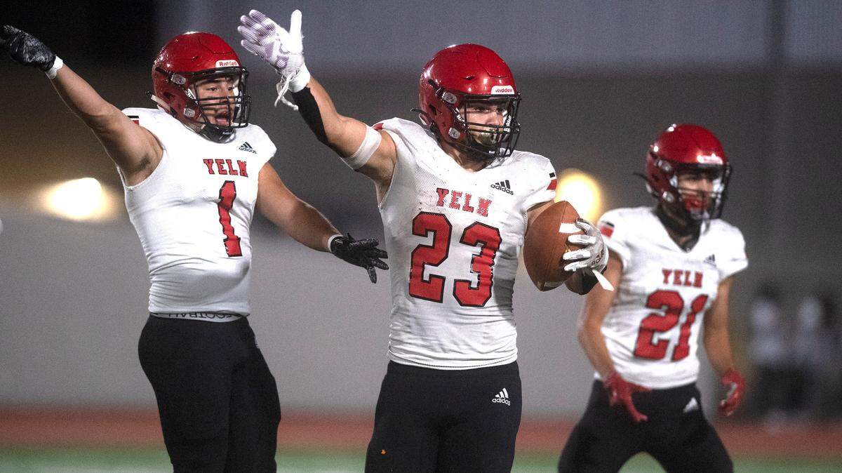 Yelm linebacker Brayden Platt (23) and teammates Ray Wright and Kristopher Hernandez celebrate Platt’s pass interception during Friday night’s high school football game against the River Ridge Hawks at South Sound Stadium in Lacey, Washington, on Sept. 24, 2021.