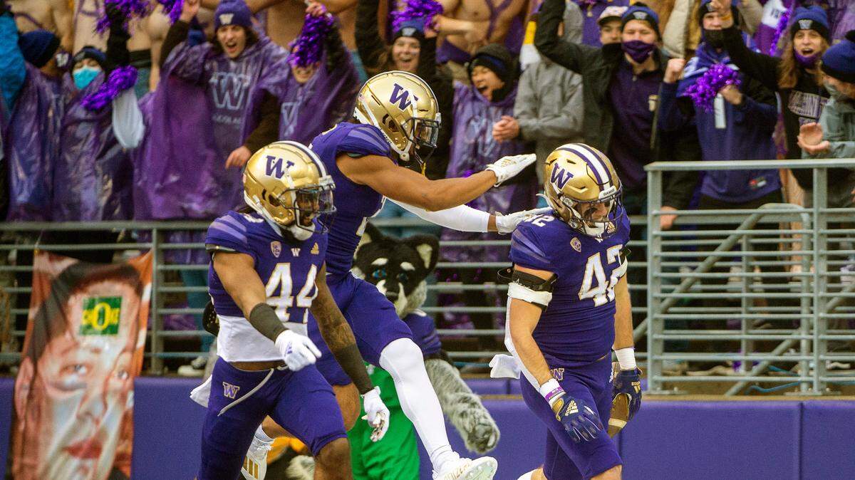 Washington defenders celebrate after linebacker Carson Bruener (42) intercepted a pass by Oregon quarterback Anthony Brown (13) during the first quarter of a Pac-12 game on Saturday at Husky Stadium in Seattle.