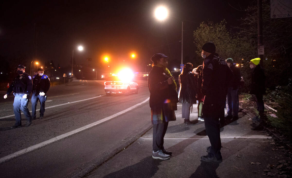 Tacoma police talk with witnesses after a woman protesting outside the Tacoma Safe meeting was hit by a hit-and-run driver outside the LeMay Car Museum in Tacoma, on Wednesday, Jan. 26, 2022.