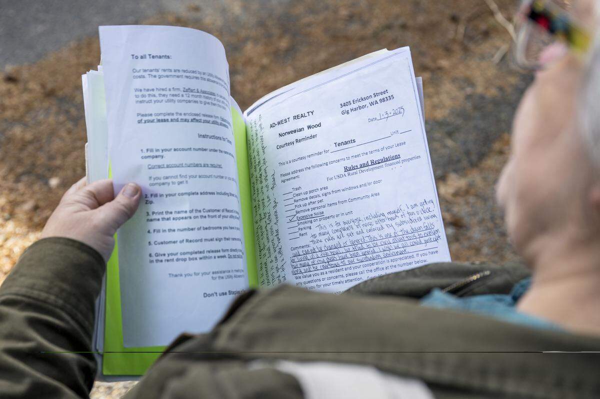 Jay Worley, a Gig Harbor resident and affordable housing advocate, flips through paperwork related to their apartment complex Norwegian Wood, on Tuesday, Nov. 11, 2025, in Gig Harbor, Wash.
