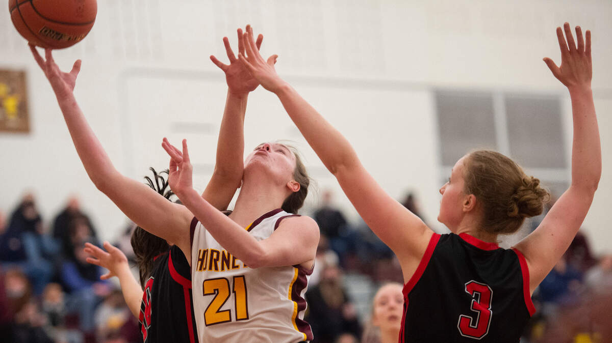 White River Hornet’s forward Ava Bright (21) drives through Sammamish Totems’s forward Kimberly Casiano (10) and Sammamish Totems’s forward Katie Anderson (3) defense during the high school girls basketball state tournament regional round game at Mount Tahoma High School in Tacoma, Wash. on Friday, Feb. 25, 2022.