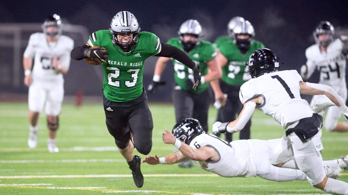 Emerald Ridge running back Logan Lisherness leaps past Eastlake defenders Ben Carollo and Colby Marsh (1) during Saturday night’s 4A state football playoff game at Sparks Stadium in Puyallup, Washington, Nov. 12, 2022. Emerald Ridge won the game, 21-9.