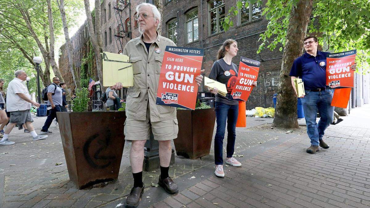 Supporters of Initiative 1639 gather signatures Monday in Seattle’s Occidental Park. From left are Gus Webster of Seattle, Pavi Chance of Edmonds and Jordan Waits of Tacoma.