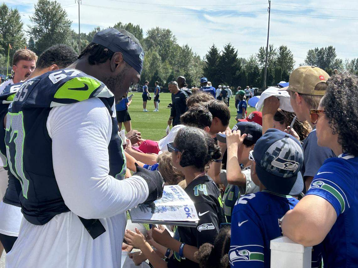 Seahawks left tackle Charles Cross signs autographs for fans following the fourth practice of Seattle’s NFL training camp Saturday, July 26, 2025, at the Virginia Mason Athletic Center in Renton.