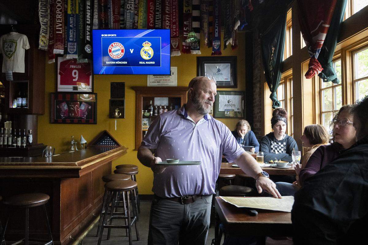 Russ Heaton, owner of Doyle's Public House, chats over the menu with Jill and Sam Theodoss, right, former Bostonians who stopped for lunch and bread pudding on Wednesday. The Tacoma bar turns 20 on Friday, April 17.