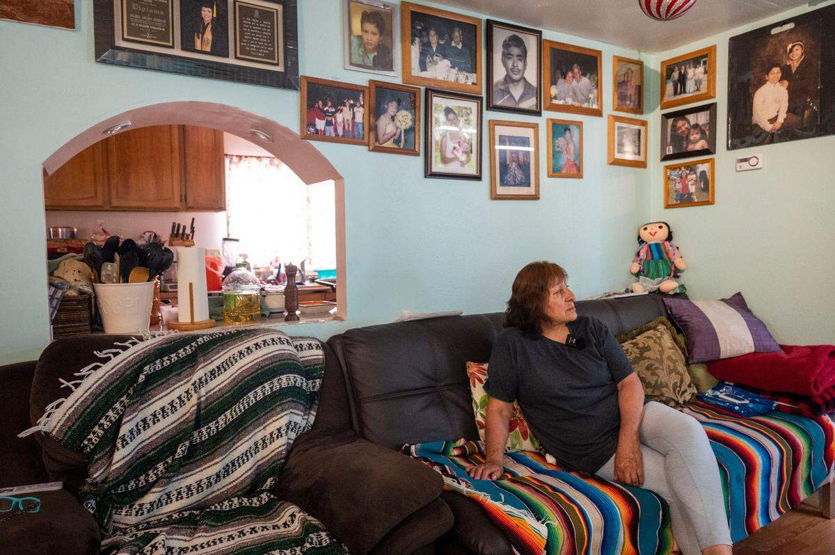 Maria Gonzalez sits on her couch underneath family pictures in the living room of their home at Meridian Estates in Puyallup, Wash., on Tuesday, July 26, 2022.