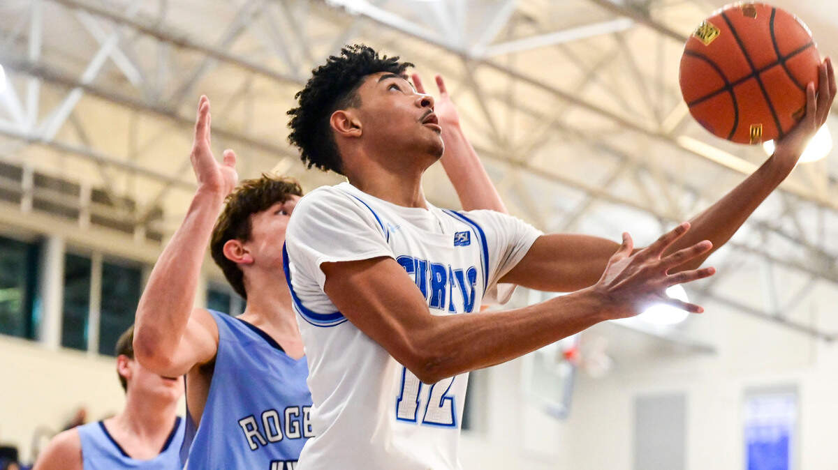 Curtis guard Cinque Maxwell (12) attempts a reverse layup as Rogers forward Gabe Tinsley (44) defends during the first quarter of a 4A South Puget Sound League tournament semifinal game on Friday, Feb. 4, 2022, at Curtis High School in University Place, Wash.