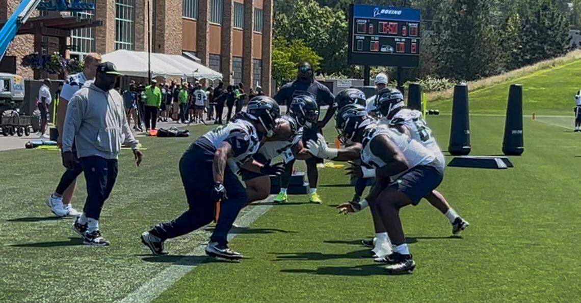 Byron Murphy (obscured, second helmet from the bottom left) and Brandon Pili (center left) charge off the snap into fellow defensive linemen during drills at the sixth practice of Seattle Seahawks organized team activities (OTAs) June 5, 2025, in Renton.