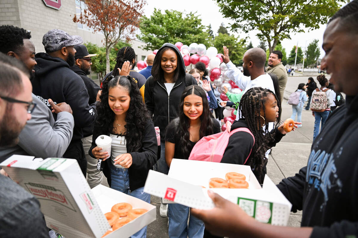 Students crowd at the end of the high-five tunnel to grab doughnuts from PUSH For Dreams on the first day of school at Gray Middle School, on Monday, Sept. 9, 2024, in Tacoma.