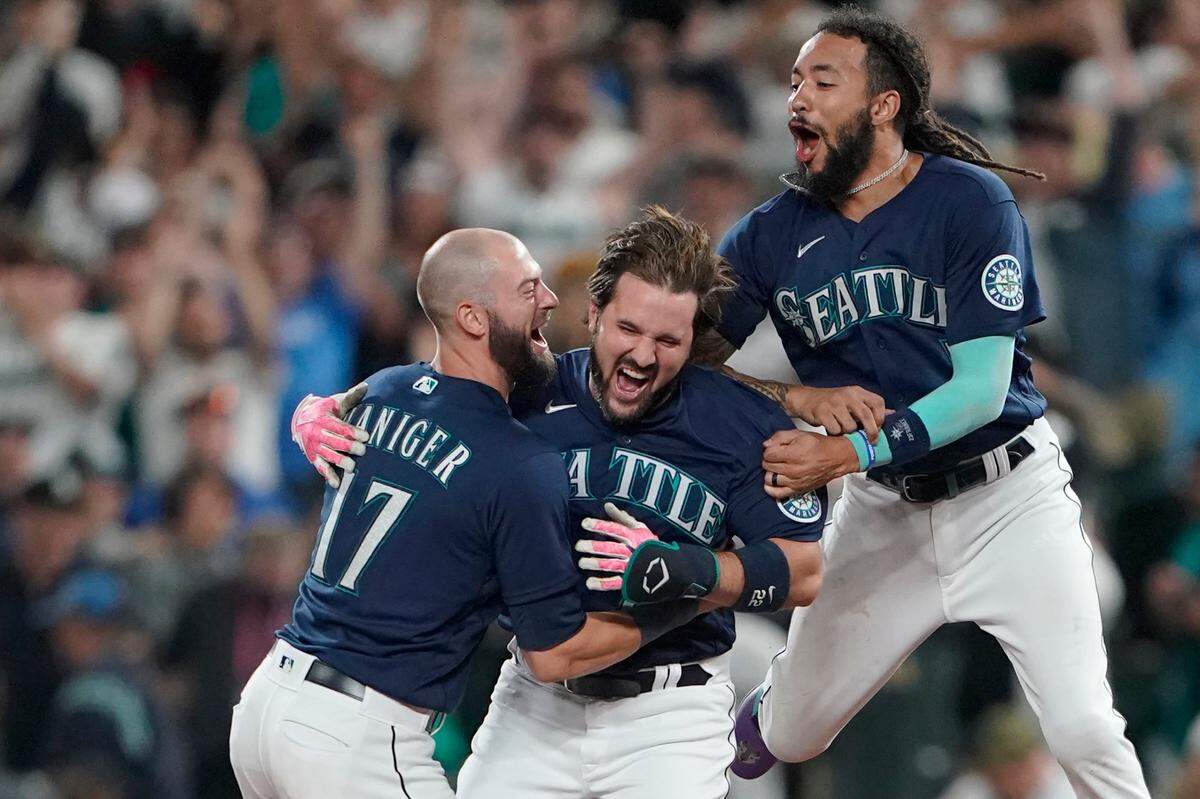 Seattle Mariners’ Luis Torrens, center, is greeted by teammates Mitch Haniger, left, and J.P. Crawford, right, after Torrens hit a walk-off RBI single to give the Mariners a 1-0 win over the New York Yankees in a 13-inning baseball game, Tuesday, Aug. 9, 2022, in Seattle. (AP Photo/Ted S. Warren)