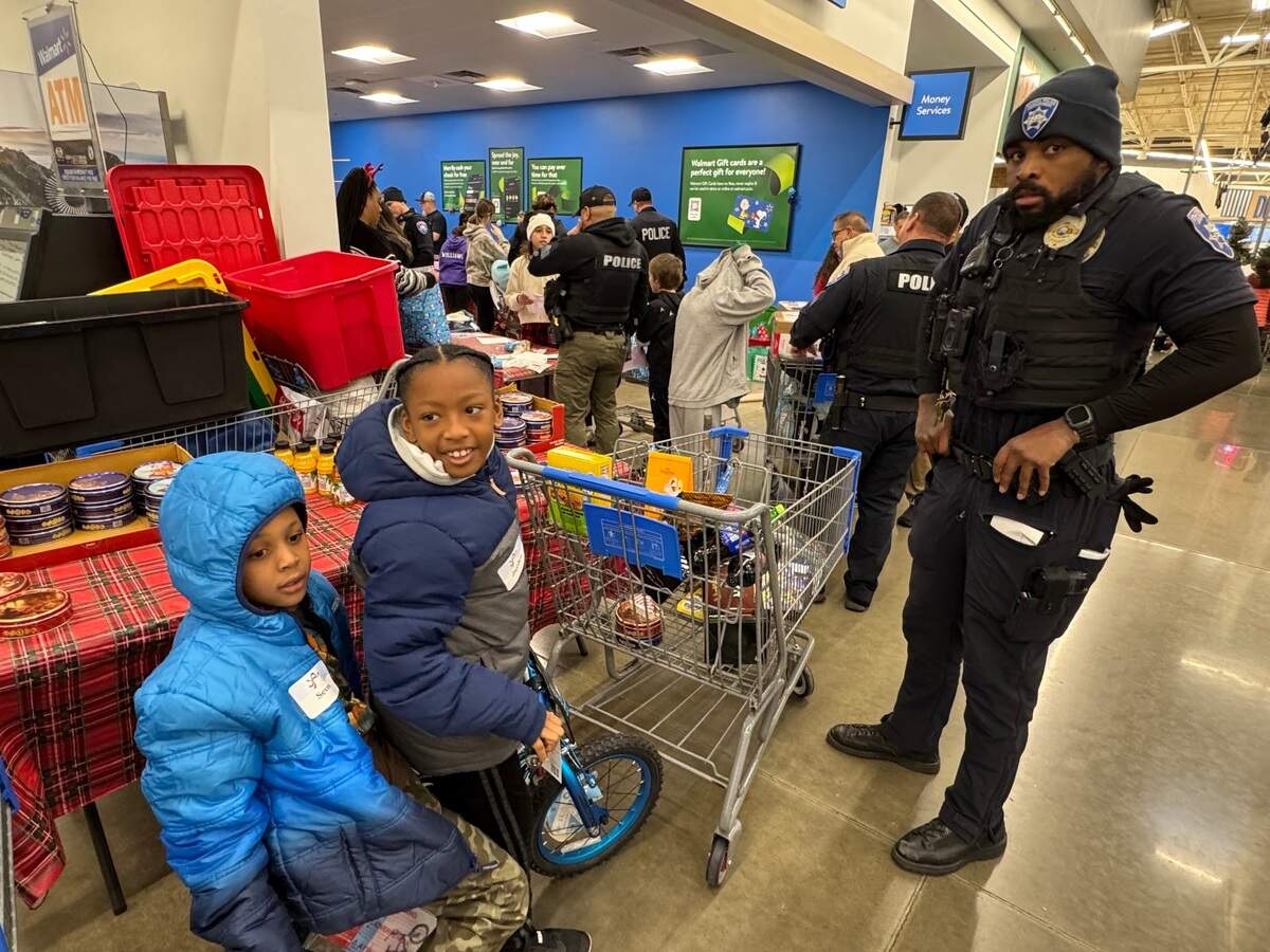 Jayden Richardson, 9, tries out his new bike with friend Seven Givens, 7, Saturday, Dec. 14, 2024 during the annual Shop With A Tacoma Cop event at Walmart in Tacoma. Officer Spencer Powell, right, came off an overnight shift to help Jayden shop.