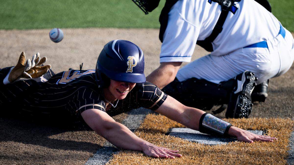 Puyallup’s DJ Ringenbach (13) slides into home plate to score a run against Curtis’s Joe Giles (13) during the baseball game at Curtis Senior High School, on Tuesday, April 15, 2025, in University Place, Wash.