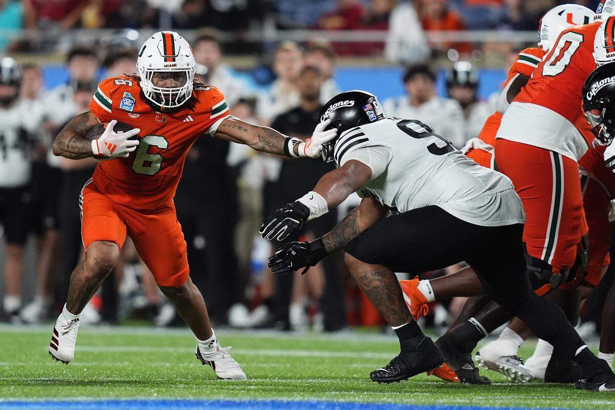 Dec 28, 2024; Orlando, FL, USA; Miami Hurricanes running back Damien Martinez (6) stiff arms Iowa State Cyclones linebacker Cael Brezina (9) during the second half at Camping World Stadium. Mandatory Credit: Jasen Vinlove-Imagn Images