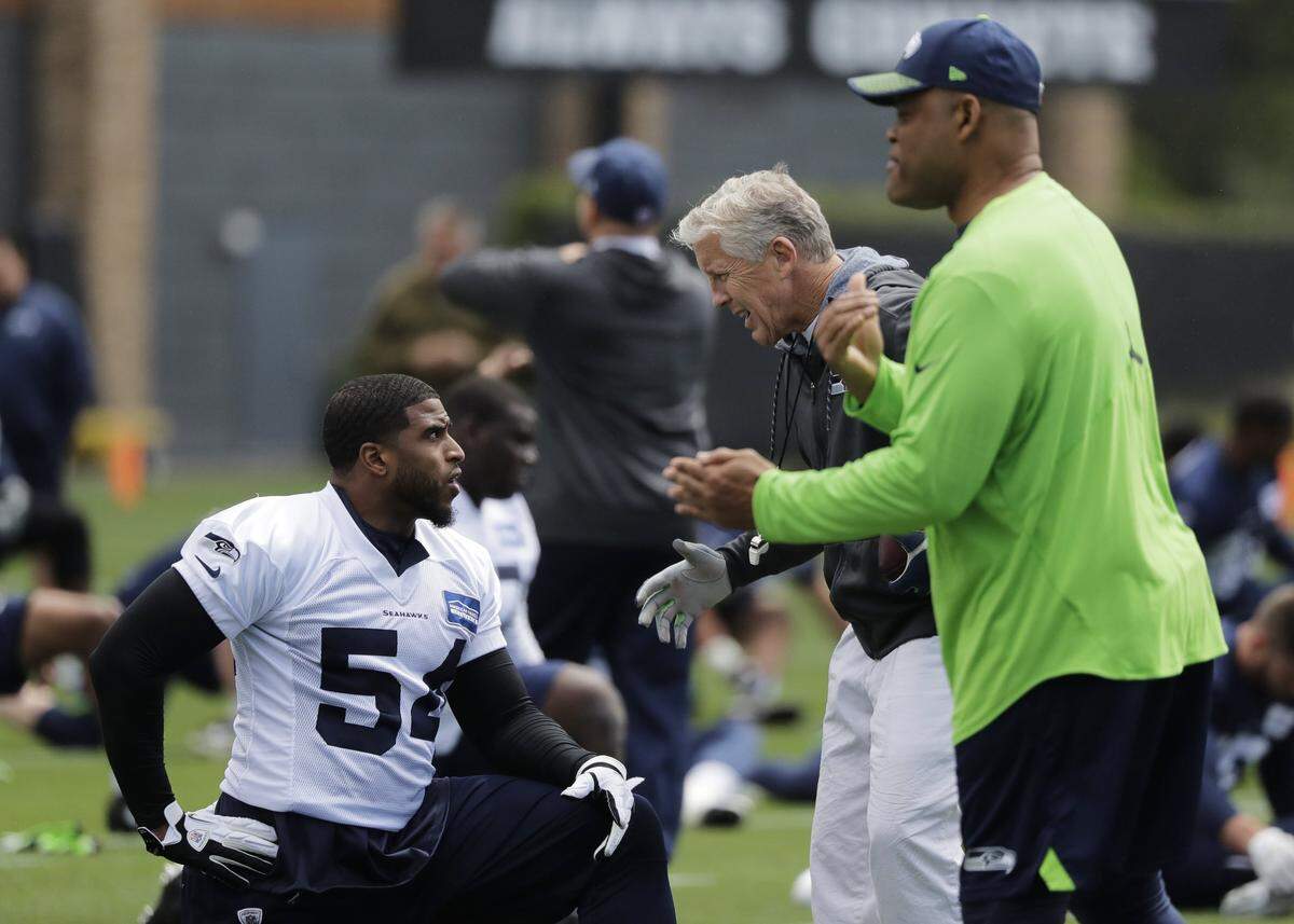 Seattle Seahawks head coach Pete Carroll, center, talks with linebacker Bobby Wagner, left, as they stretch near defensive coordinator Ken Norton Jr., right, during NFL football practice, Monday, June 4, 2018, in Renton, Wash. (AP Photo/Ted S. Warren)