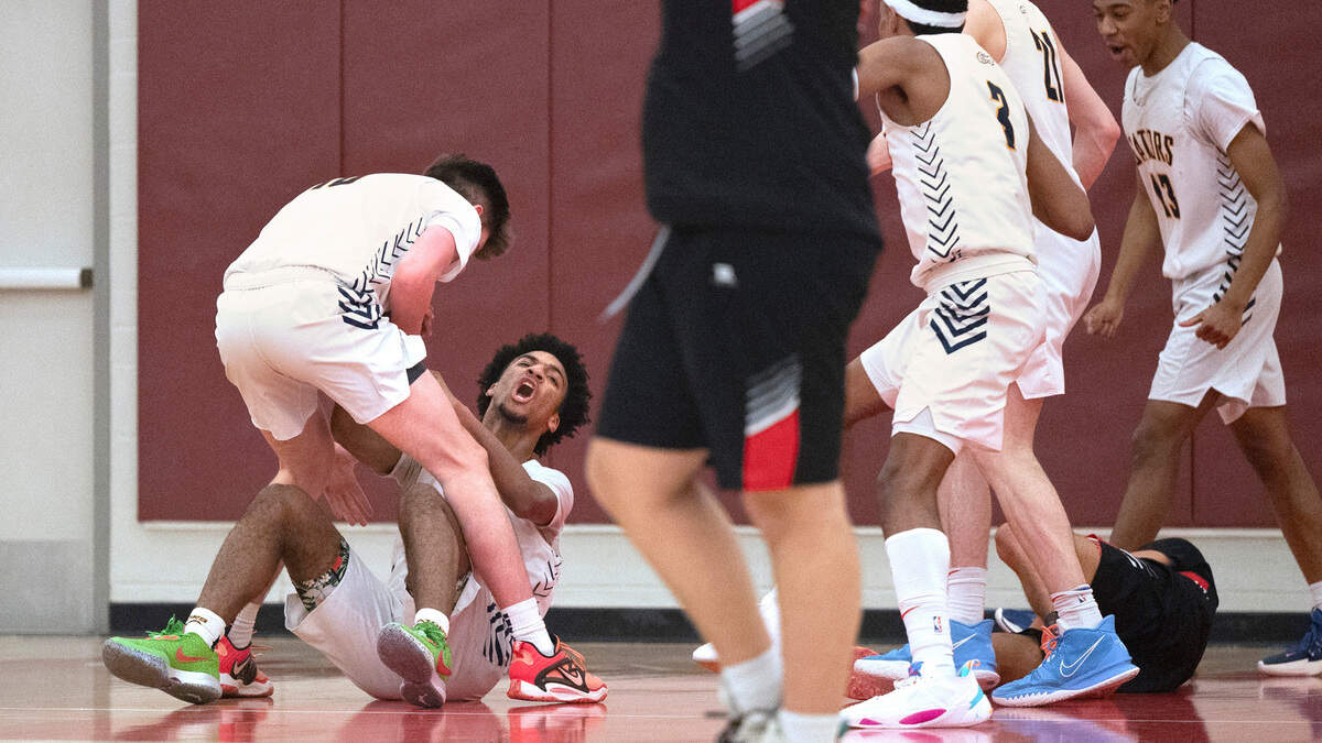 Annie Wright’s Reggie Lester (on floor) celebrates with teammate Cale Carter after drawing an offensive foul on Seattle Christian’s Jordan Clark during the 1A West Central District boys basketball championship game at Mount Tahoma High School in Tacoma, Washington, on Wednesday, Feb. 15, 2023. Annie Wright battled from behind, then held off multiple Warrior runs to win, 65-60.