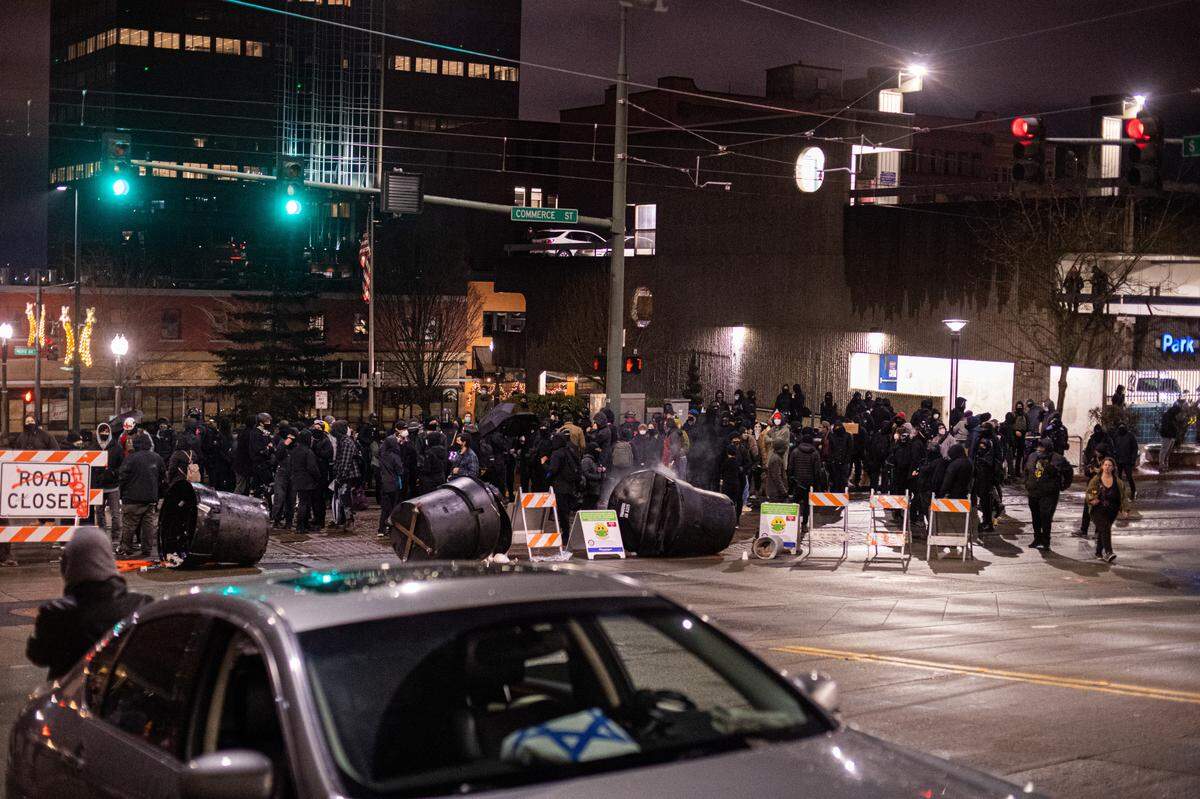 Protesters form a makeshift roadblock near South 9th Street and Commerce Street in Tacoma, Wash., on Sunday, Jan. 24, 2021. Protesters arrived in Tacoma following videos on social media the night before of a Tacoma police officer driving through a crowd of people at a street race.