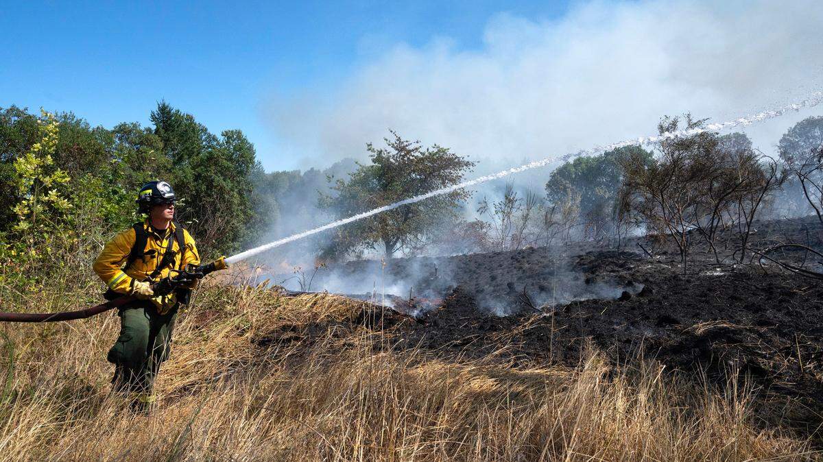 Central Pierce firefighter Jackson Mosely knocks down hot spots at a brush wildfire at Fort Steilacoom Park in Tacoma, Washington, on Wednesday, Aug. 16, 2023.