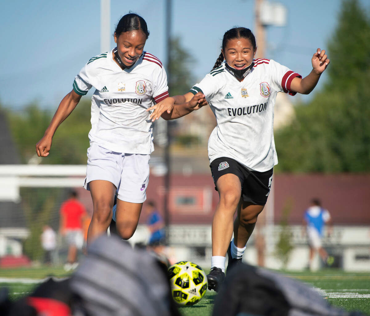 Mia Marcelle (left) races teammate Kayla Tarver to the ball during practice for the South Tacoma United Evolution U13 girls soccer team at Stewart Middle School in Tacoma, Washington, on Tuesday, July 13, 2021. The team will be competing in the national championship tournament in Colorado starting Friday.