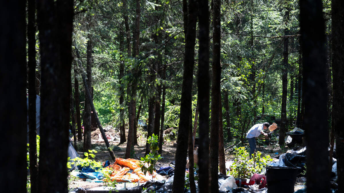 A man cleans up trash and debris inside “The Jungle,” the informal name of a homeless encampment near the 9700 block of Steele Street South on May 25, 2023, in Tacoma.