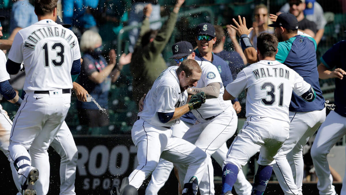 Seattle Mariners players surround Tom Murphy, center, after he hit a sacrifice fly, scoring the winning run, in the 10th inning against the Oakland Athletics during a baseball game, Monday, May 31, 2021, in Seattle. (AP Photo/John Froschauer)