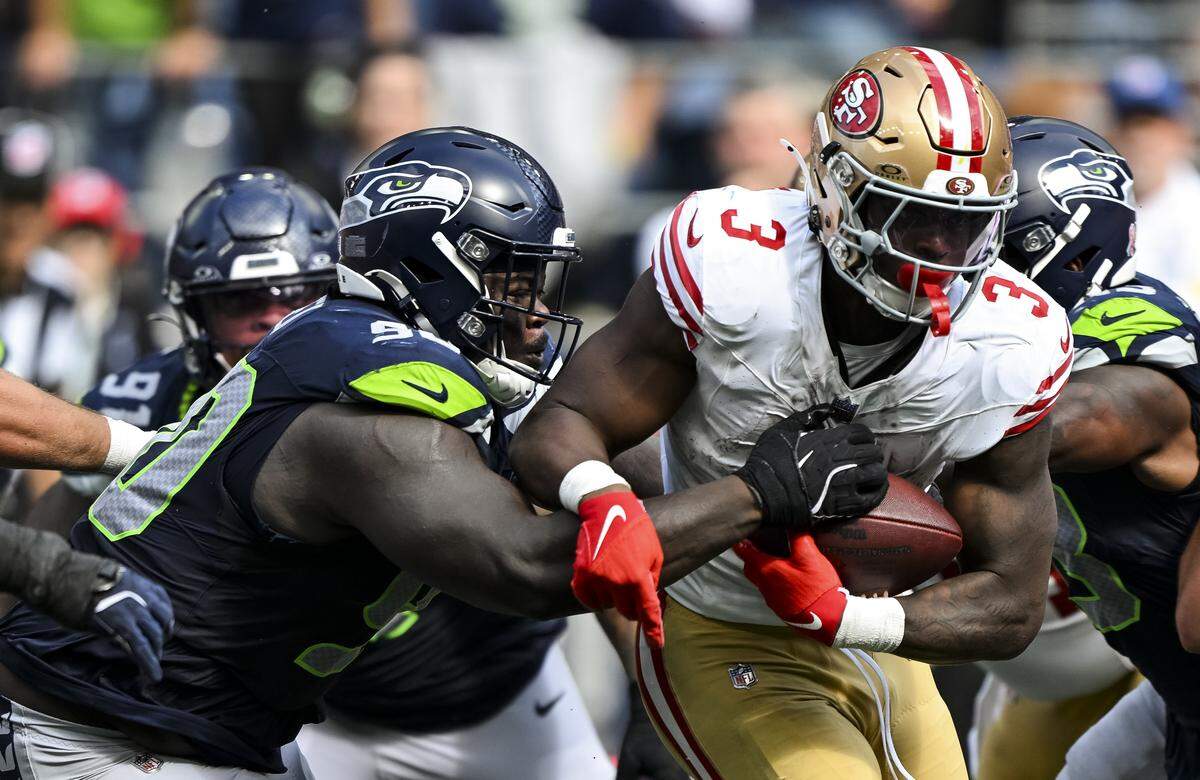 San Francisco 49ers running back Brian Robinson Jr. (3) carries the ball as Seattle Seahawks defensive tackle Jarran Reed (90) tries to punch it out during the fourth quarter of the game at Lumen Field, on Sunday, Sept. 7, 2025, in Seattle.