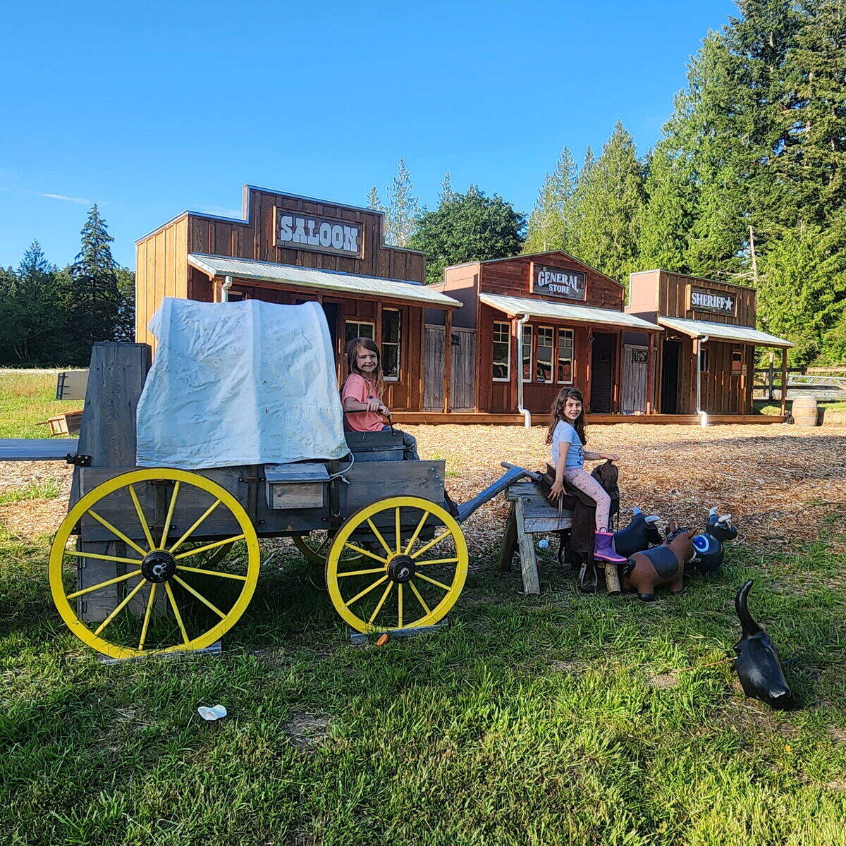 The Himenes’ daughter and niece play in Harbor Farms’ replica of a Western town, which includes a covered wagon and a saloon, general store and sheriff’s office.