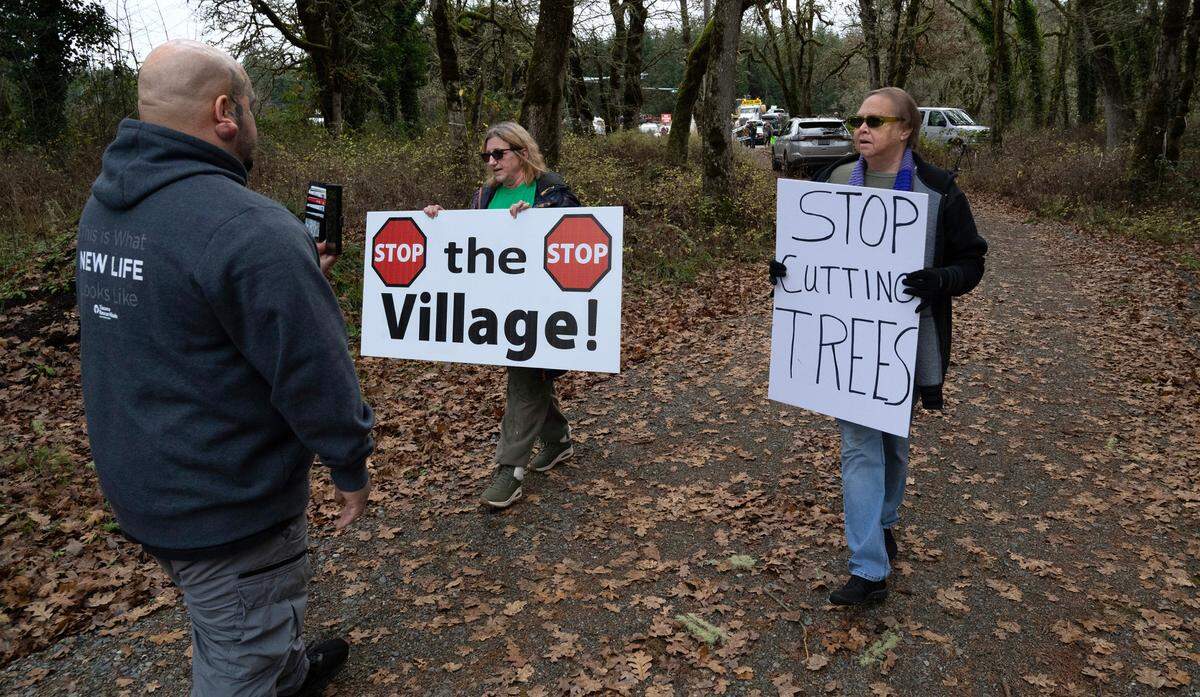 Two protesters walk past security guards at the groundbreaking ceremonies at the site of the new Good Neighbor Village in Spanaway, Washington, on Thursday, Nov. 21, 2024. The women left the property on their own a few minutes later.