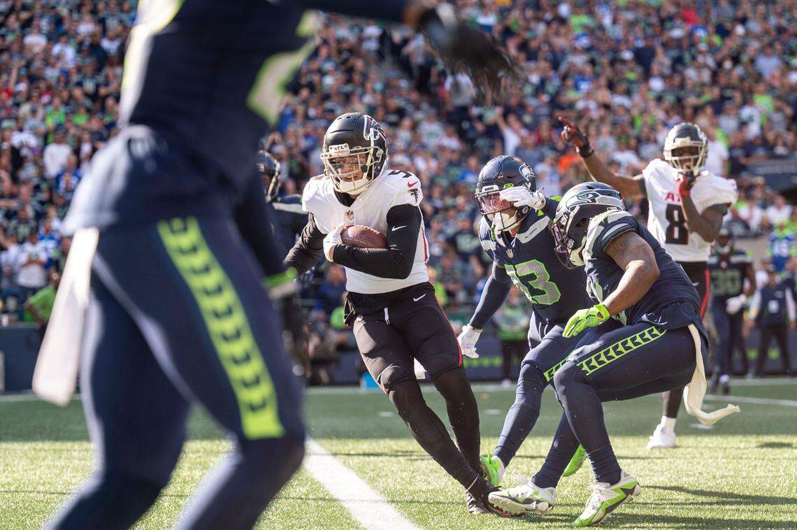 After catching a pass from quarterback Marcus Mariota (1), Atlanta Falcons wide receiver Drake London (5) breaks through a tackle attempt by Seattle Seahawks strong safety Josh Jones (13) and safety Quandre Diggs (6) on his way into the endzone during the third quarter of an NFL game on Sunday, Sept. 25, 2022, at Lumen Field in Seattle.