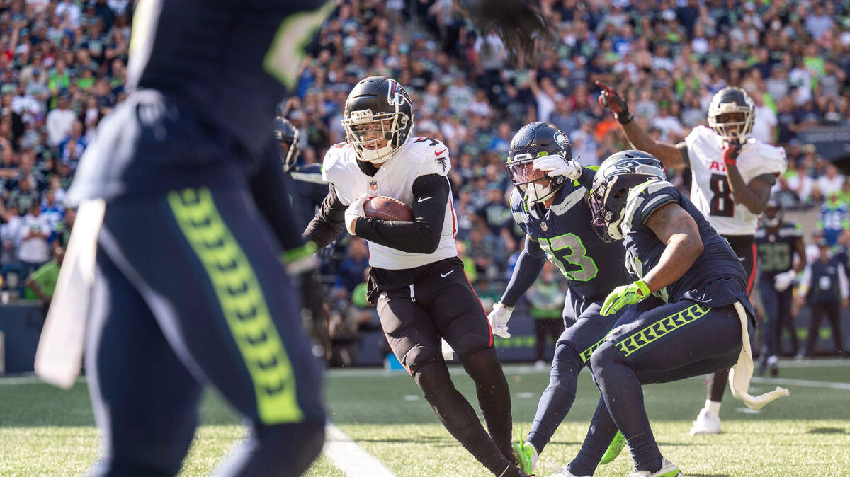 After catching a pass from quarterback Marcus Mariota (1), Atlanta Falcons wide receiver Drake London (5) breaks through a tackle attempt by Seattle Seahawks strong safety Josh Jones (13) and safety Quandre Diggs (6) on his way into the endzone during the third quarter of an NFL game on Sunday, Sept. 25, 2022, at Lumen Field in Seattle.