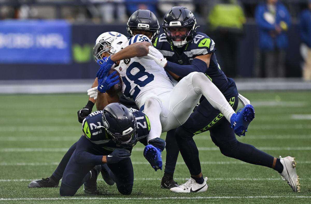 Indianapolis Colts running back Jonathan Taylor (28) is tackled by Seattle Seahawks cornerback Devon Witherspoon (21), safety Coby Bryant (8) and safety Julian Love (20) during the third quarter of the game at Lumen Field, on Sunday, Dec. 14, 2025, in Seattle.